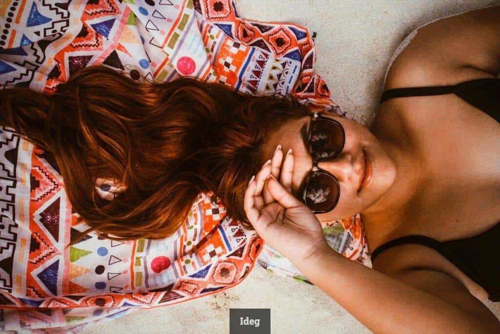 A woman laying on a blanket with sunglasses on